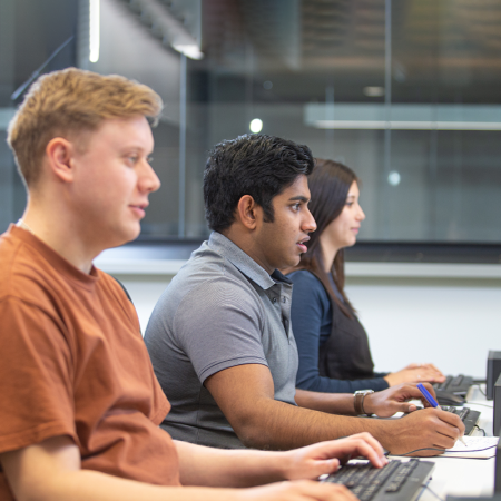 Three students sitting at desktop computers